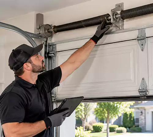 Technician inspecting a garage door spring system in Indianapolis