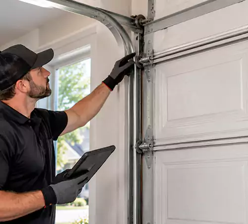 Technician inspecting garage door track and roller alignment in Indianapolis